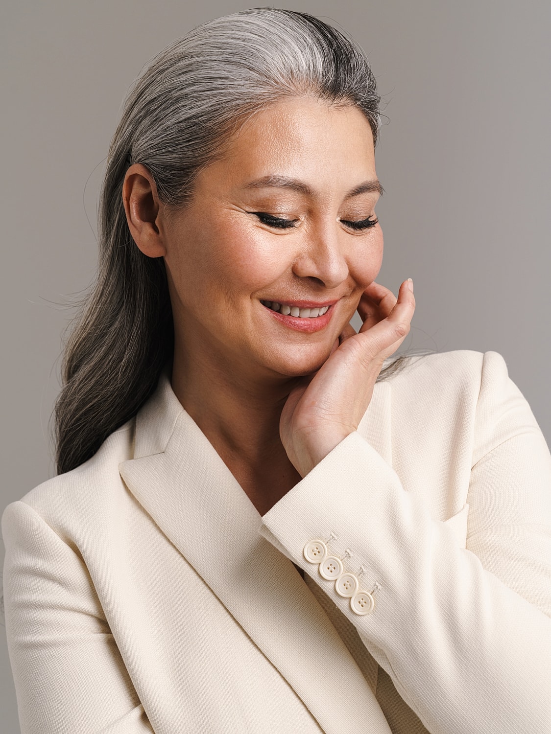 Smiling woman with gray hair in blazer.
