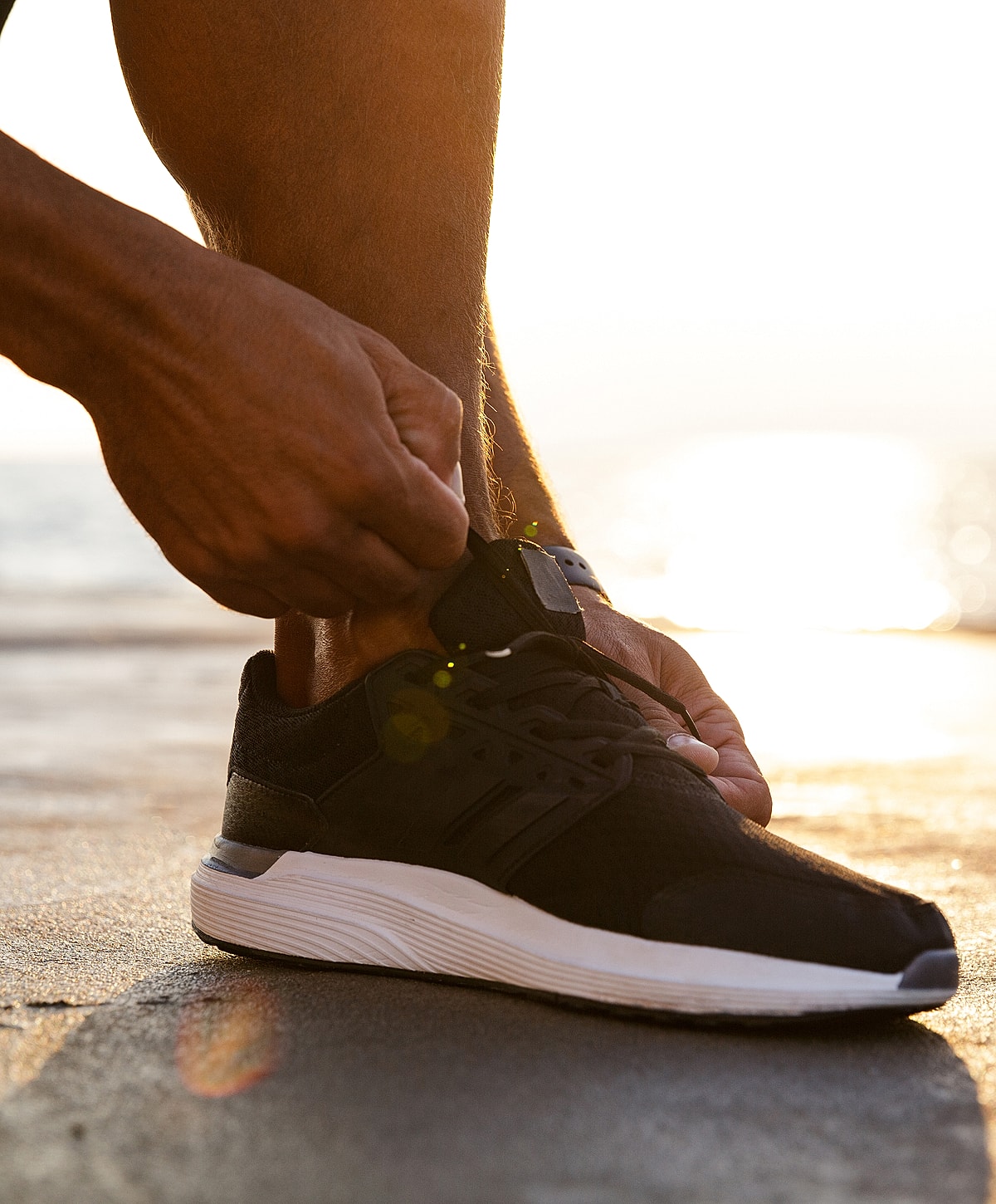 Person tying shoelaces at sunset.
