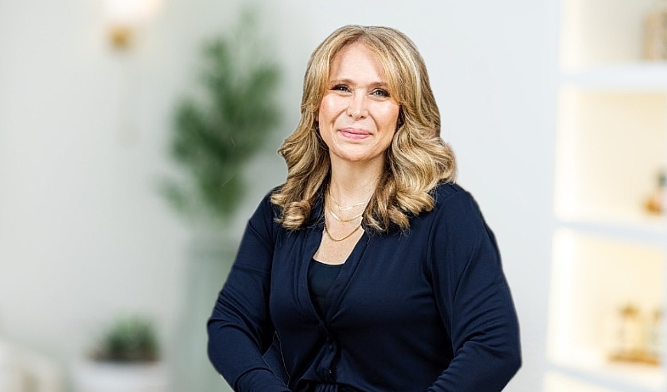 Smiling woman with wavy hair in cozy setting.