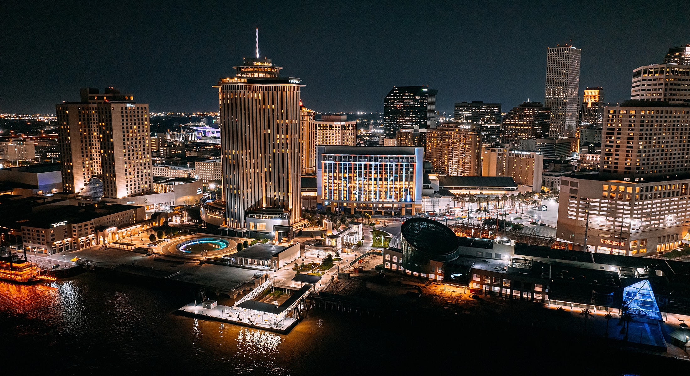 Nighttime cityscape with illuminated buildings and waterfront.