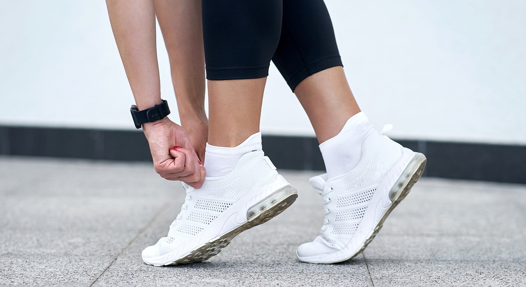 Adjusting white athletic shoes before exercise.
