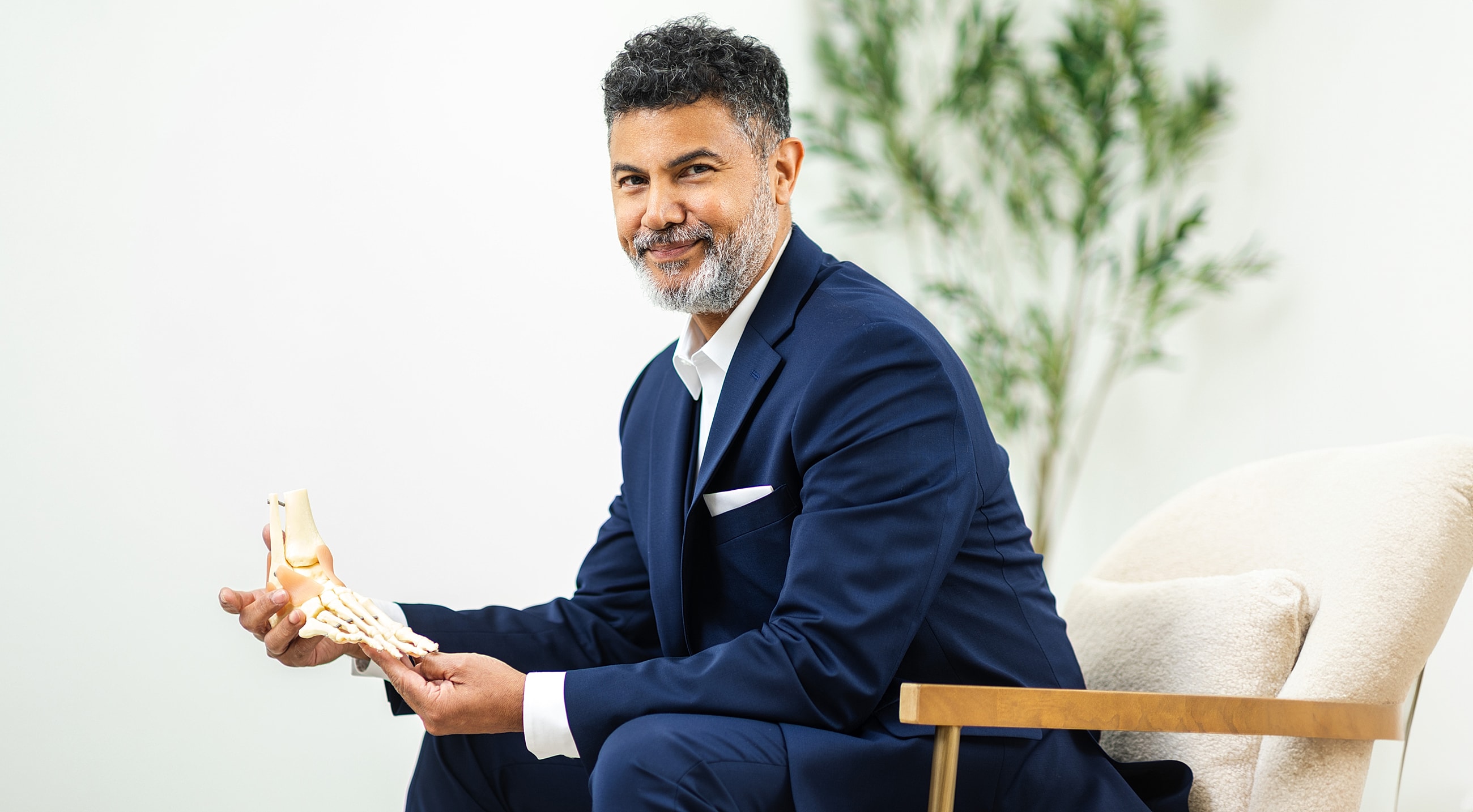 Man in suit holding foot model, smiling.