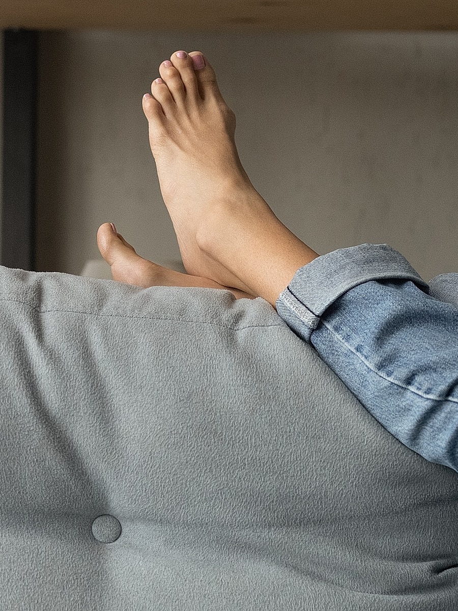 Relaxed feet on a couch with denim jeans.