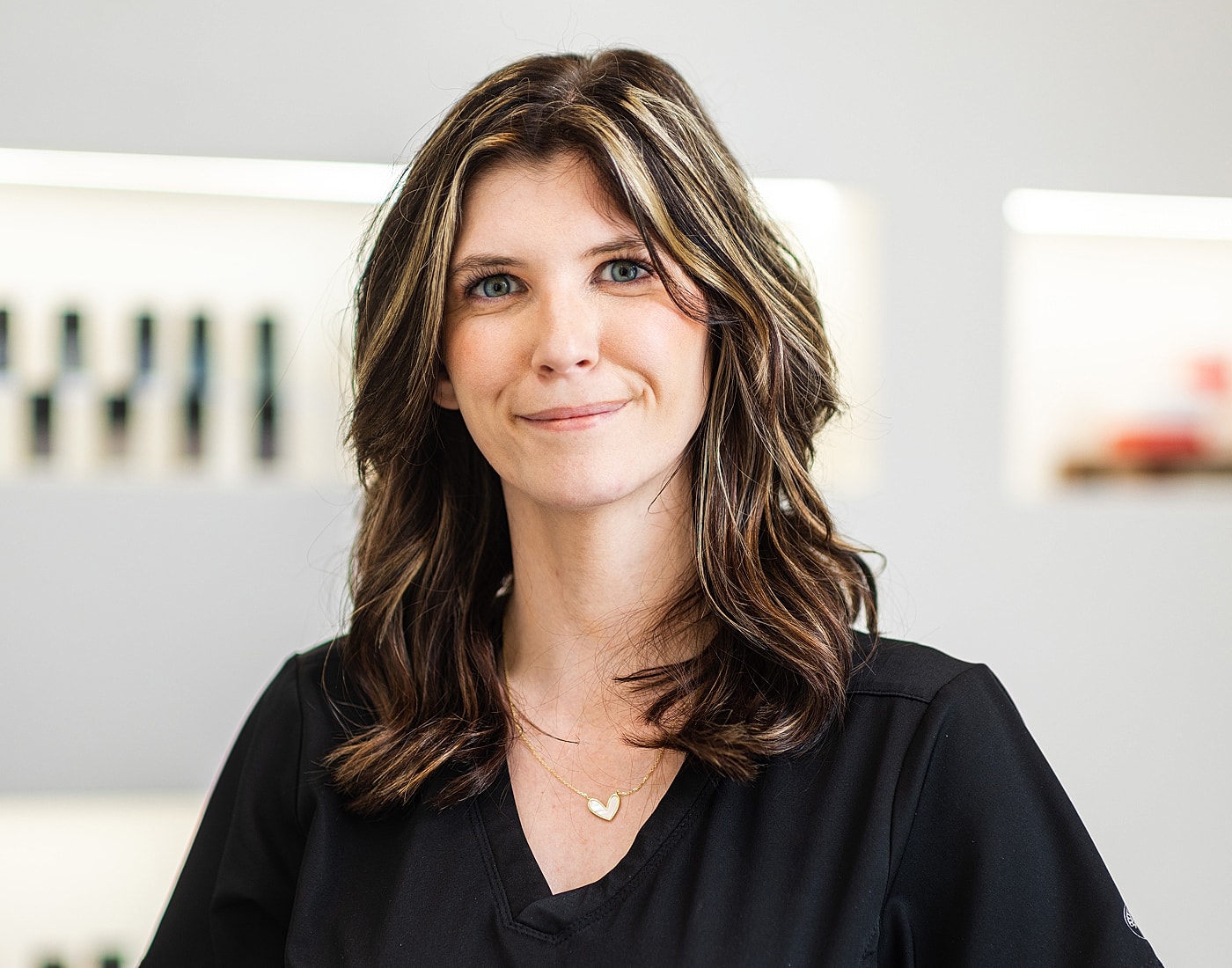 Smiling woman in black uniform, neutral background.
